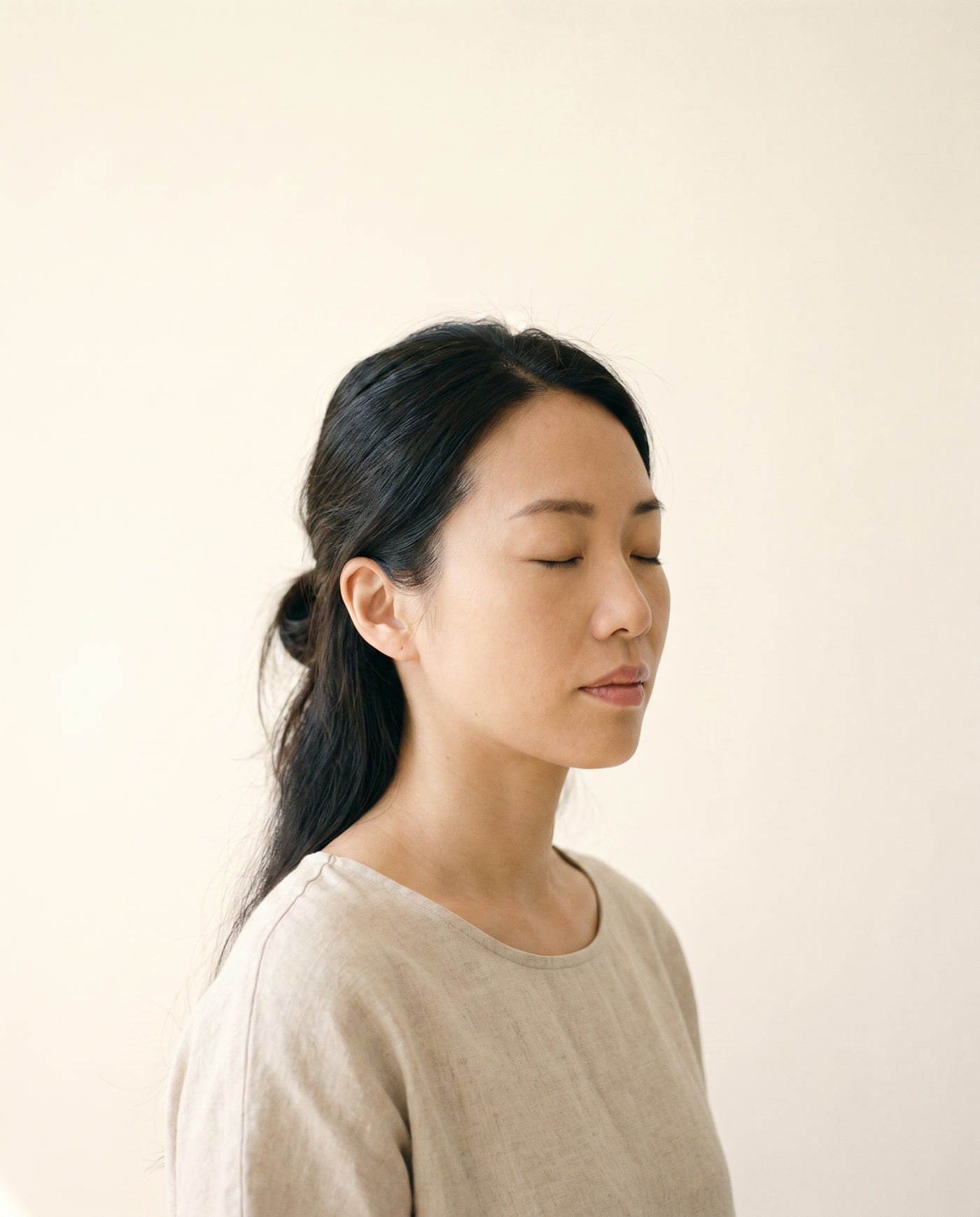 A woman with her eyes closed in soft morning light, about to say a few words.