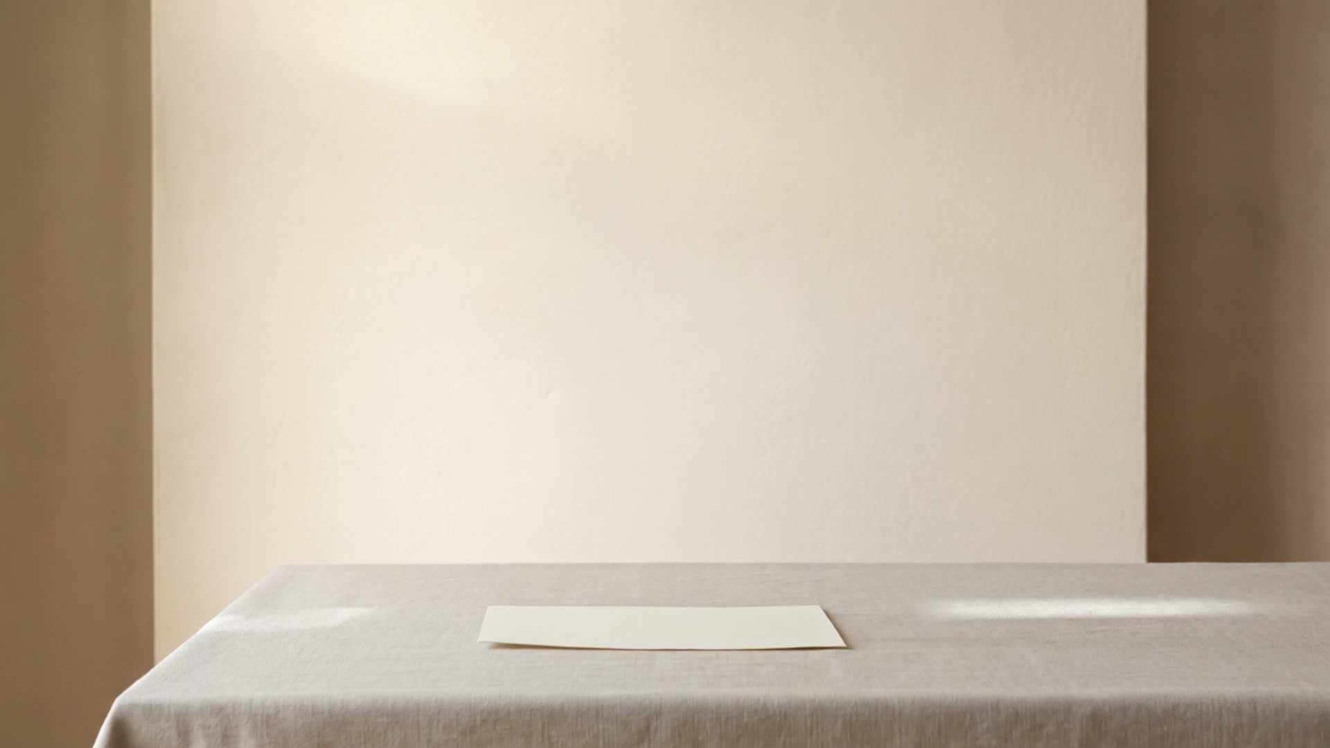 A single sheet of paper resting on linen in soft daylight.